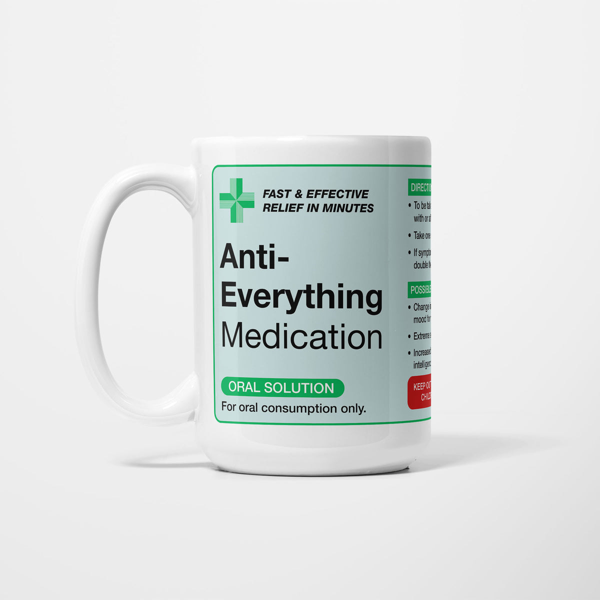 The 15oz Anti-Everything Medication mug, white ceramic with a pale green pharmacy label reading 'Anti-Everything Medication — oral solution, for oral consumption only', a green first-aid cross beside it