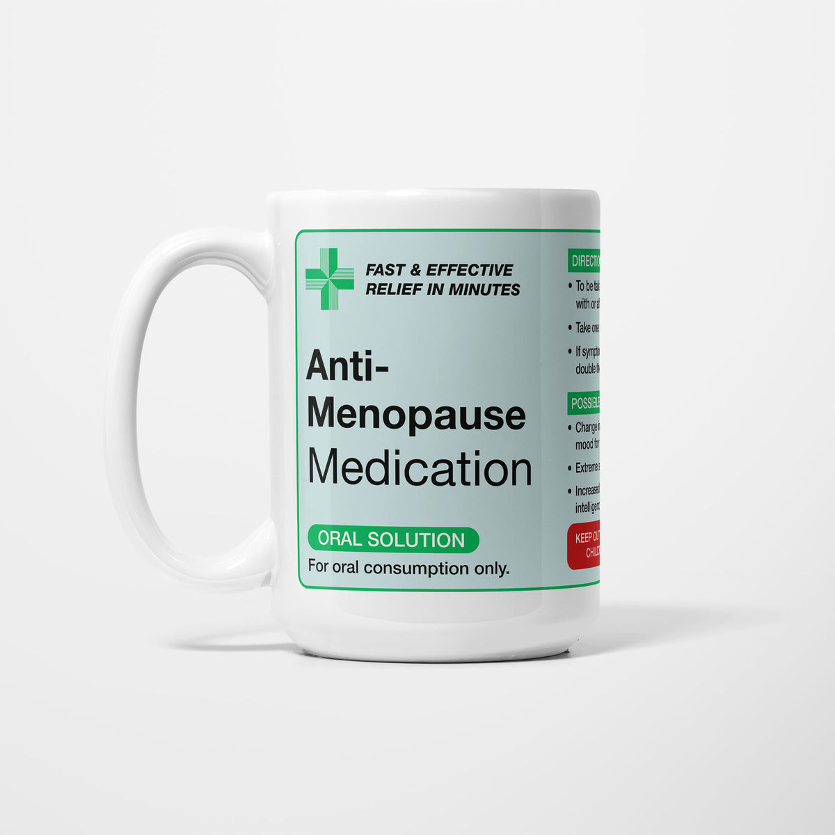The 15oz Anti-Menopause Medication mug, white ceramic with a pale green pharmacy label reading 'Anti-Menopause Medication — oral solution, for oral consumption only', a green first-aid cross beside it
