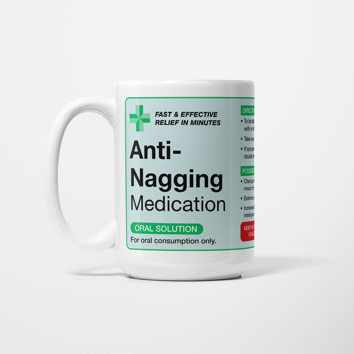 The 15oz Anti-Nagging Medication mug, white ceramic with a pale green pharmacy label reading 'Anti-Nagging Medication — oral solution, for oral consumption only', a green first-aid cross beside it
