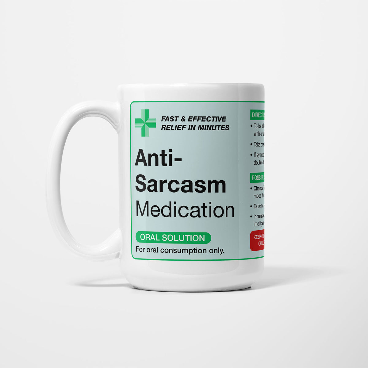 The 15oz Anti-Sarcasm Medication mug, white ceramic with a pale green pharmacy label reading 'Anti-Sarcasm Medication — oral solution, for oral consumption only', a green first-aid cross beside it
