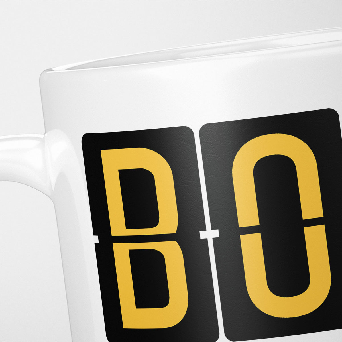 Close crop of the Bournemouth Airport Tag mug, gold split-flap tiles reading 'B' and 'O' on black — the first two letters of BOH