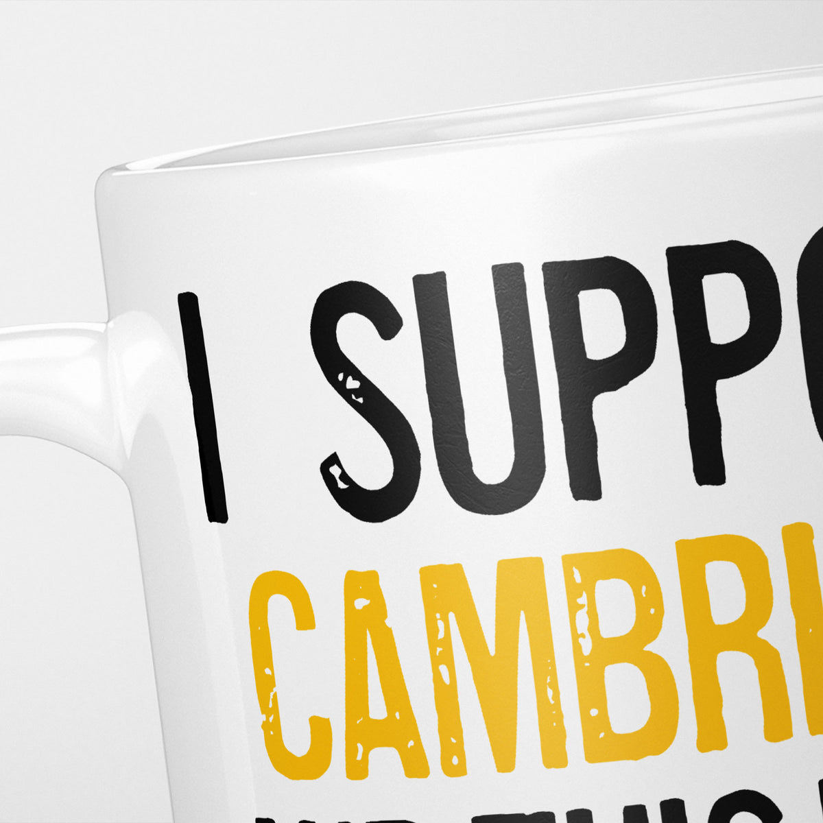 Close crop of the I Support Cambridge mug, 'I Support' in heavy black above the club name in amber, running off the edge of the frame