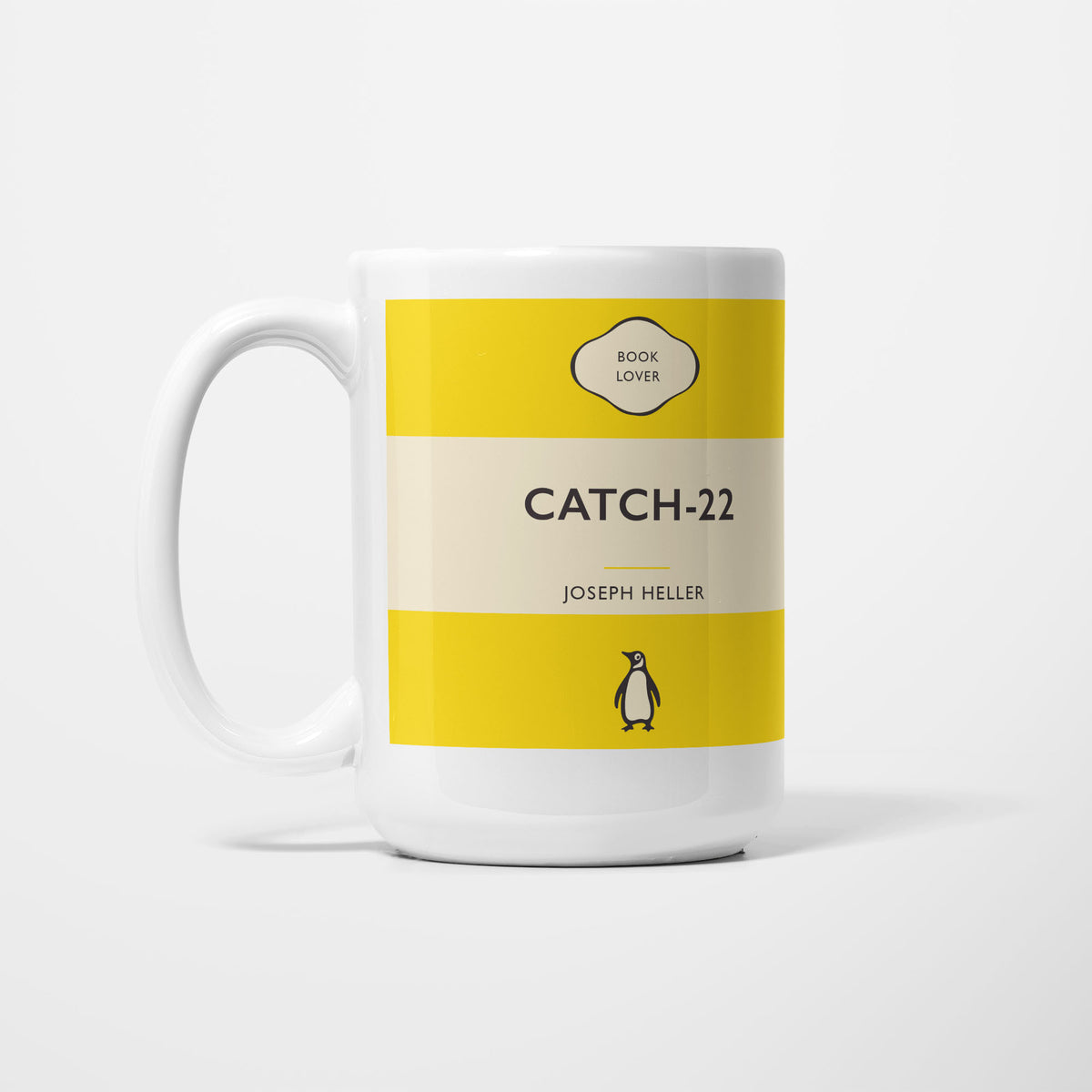 The 15oz Catch 22 mug, white ceramic printed as a vintage paperback jacket in yellow and cream, reading 'Catch-22' above Joseph Heller