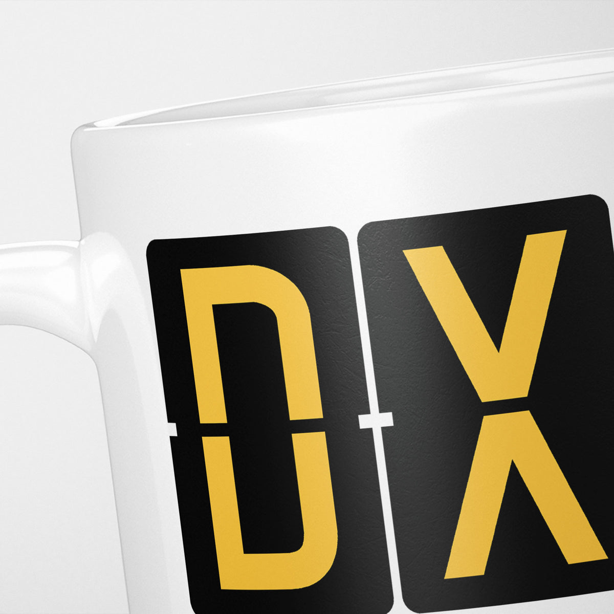 Close crop of the Dubai Airport Tag mug, gold split-flap tiles reading 'D' and 'X' on black — the first two letters of DXB