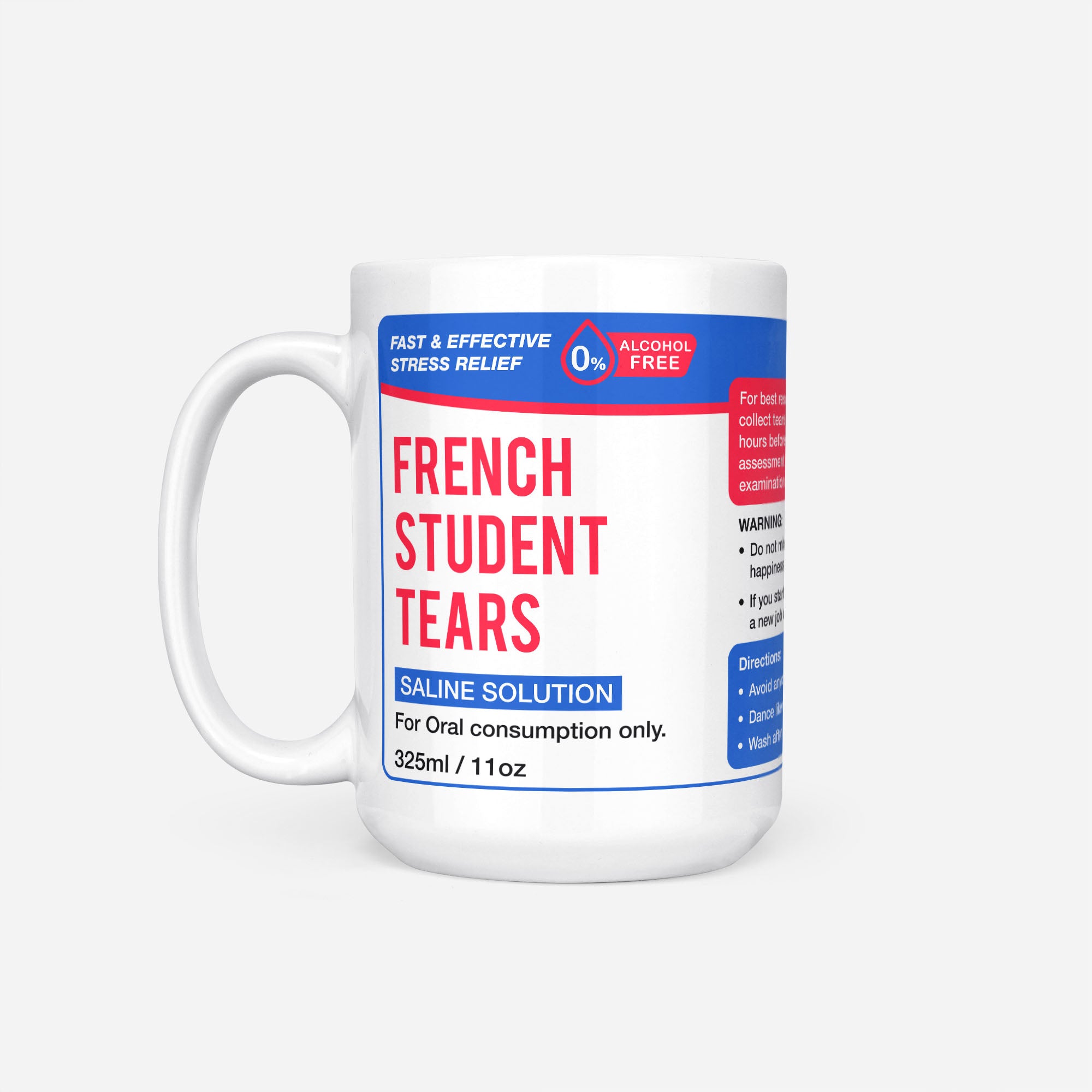 The 15oz French Student Tears mug, white ceramic with a blue pharmacy-style label reading 'French Student Tears — Saline Solution, for oral consumption only'