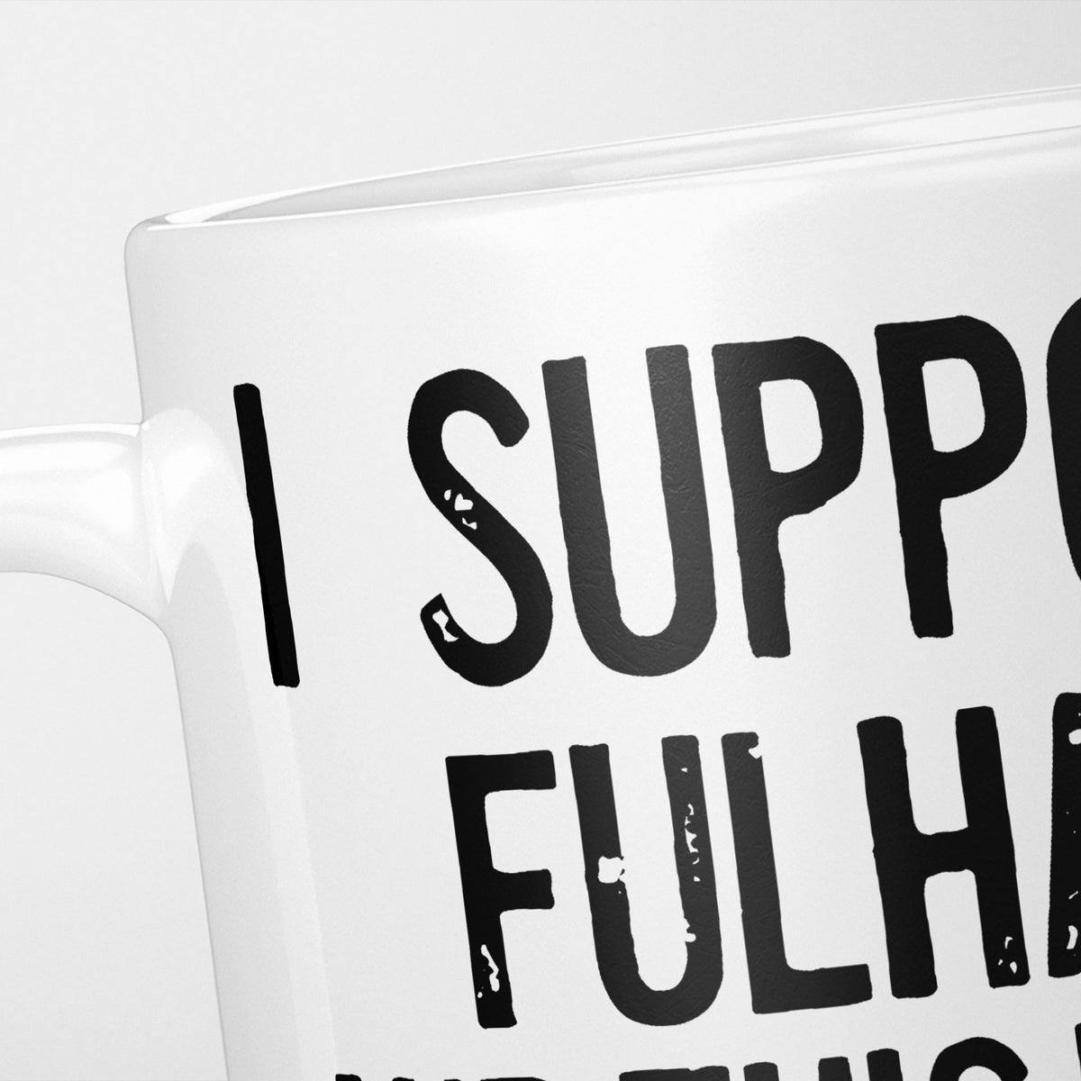 Close crop of the I Support Fulham mug, 'I Support' above the club name in heavy black type, running off the edge of the frame