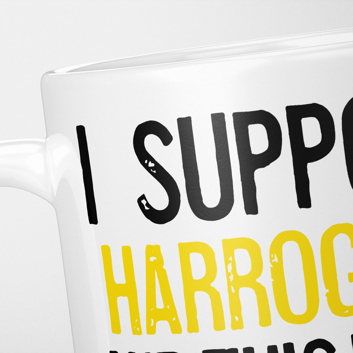 Close crop of the I Support Harrogate mug, 'I Support' in heavy black above the club name in yellow, running off the edge of the frame