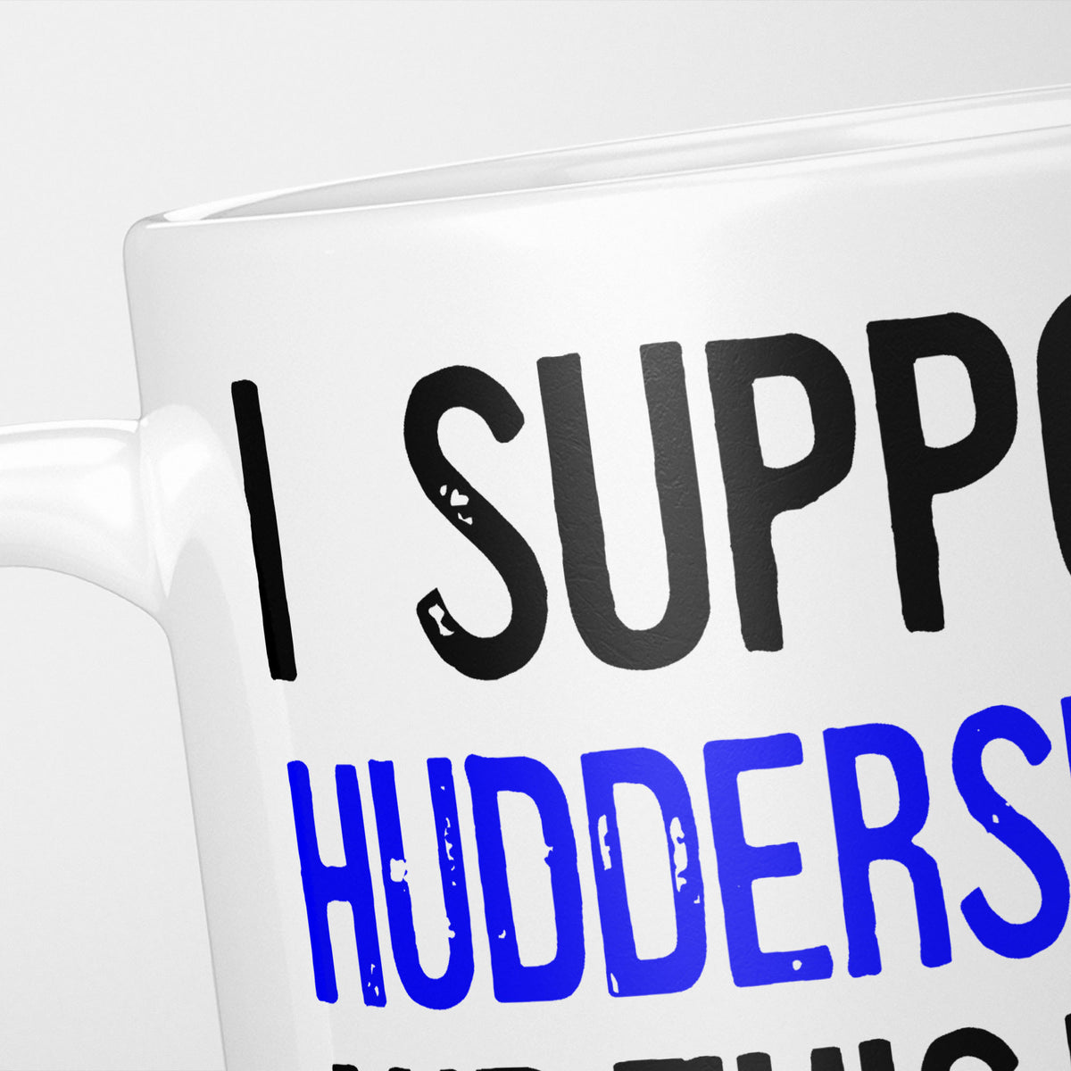 Close crop of the I Support Huddersfield mug, 'I Support' in heavy black above the club name in blue, running off the edge of the frame
