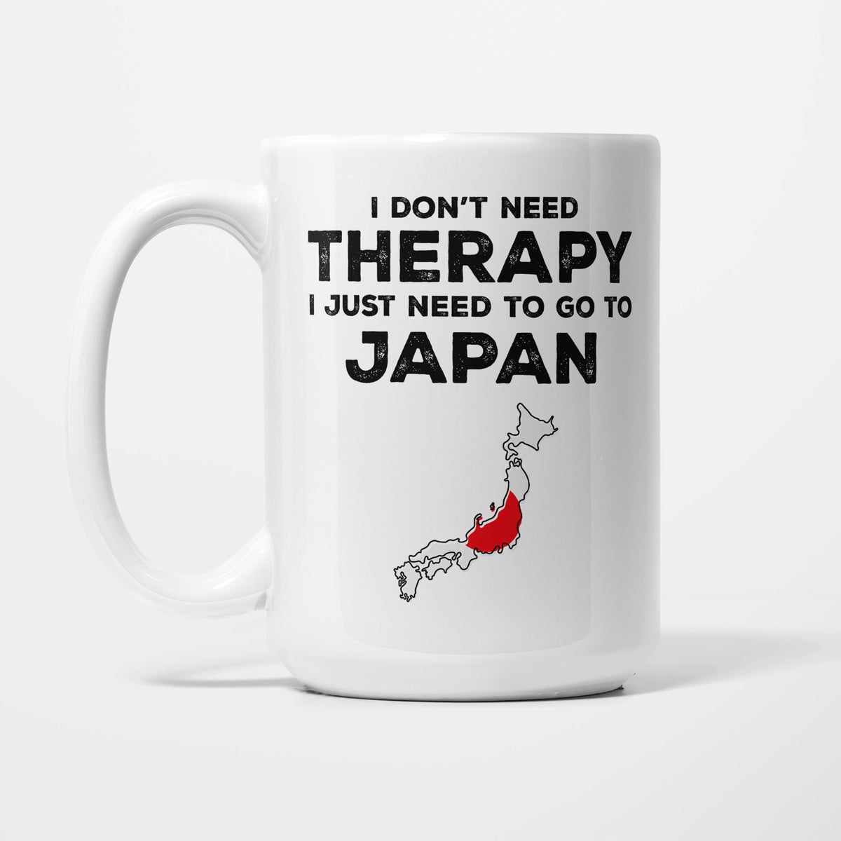 The 15oz I Need Japan mug, white ceramic in bold black type reading 'I don't need therapy, I just need to go to JAPAN', above an outline of Japan filled with its national flag