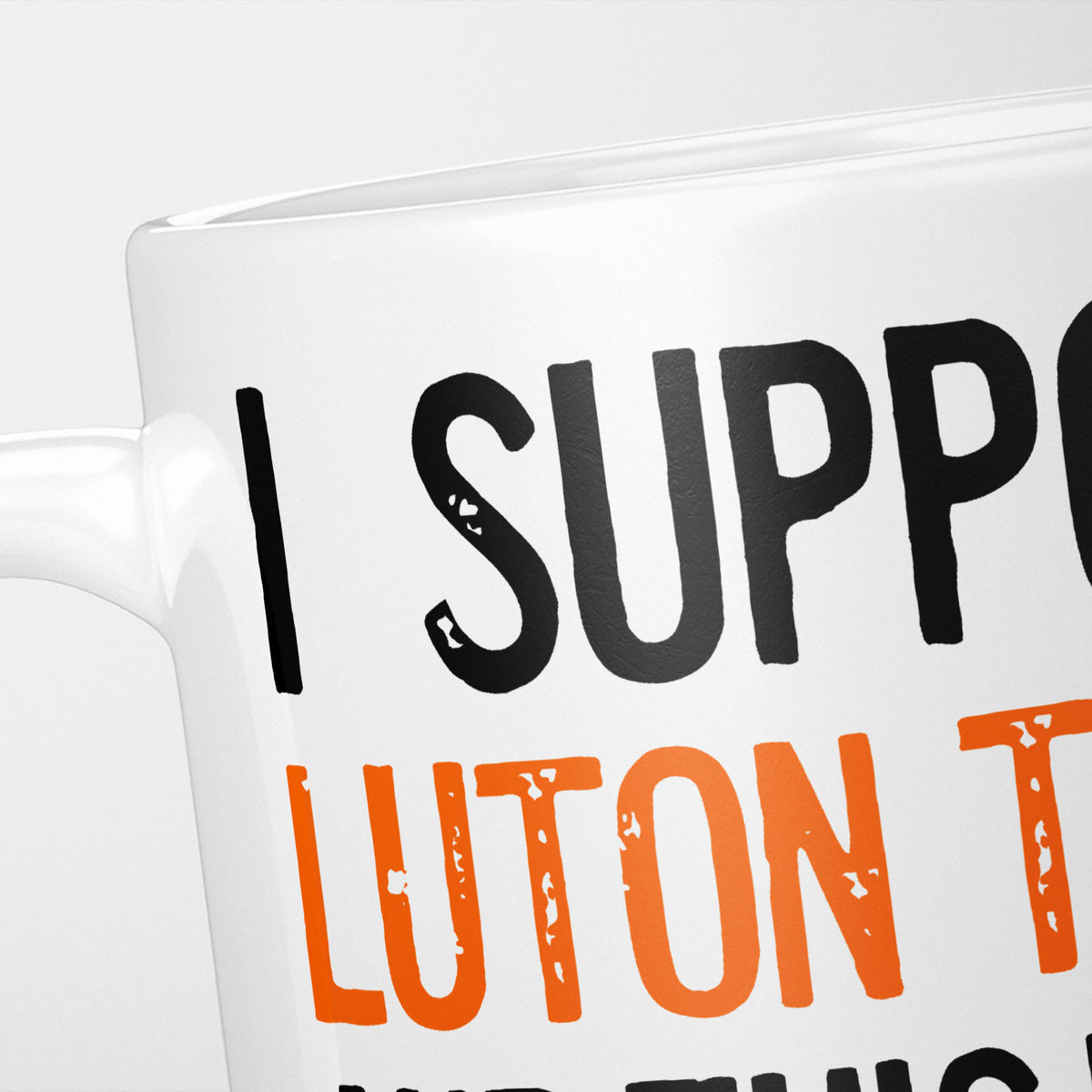 Close crop of the I Support Luton Town mug, 'I Support' in heavy black above the club name in orange, running off the edge of the frame