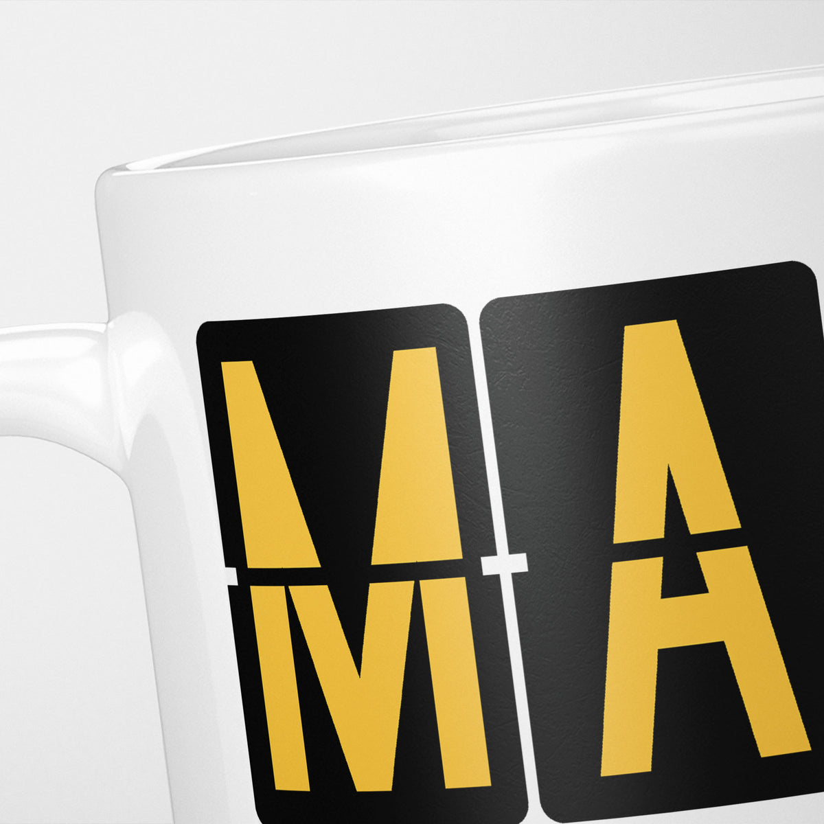 Close crop of the Madrid Airport Tag mug, gold split-flap tiles reading 'M' and 'A' on black — the first two letters of MAD