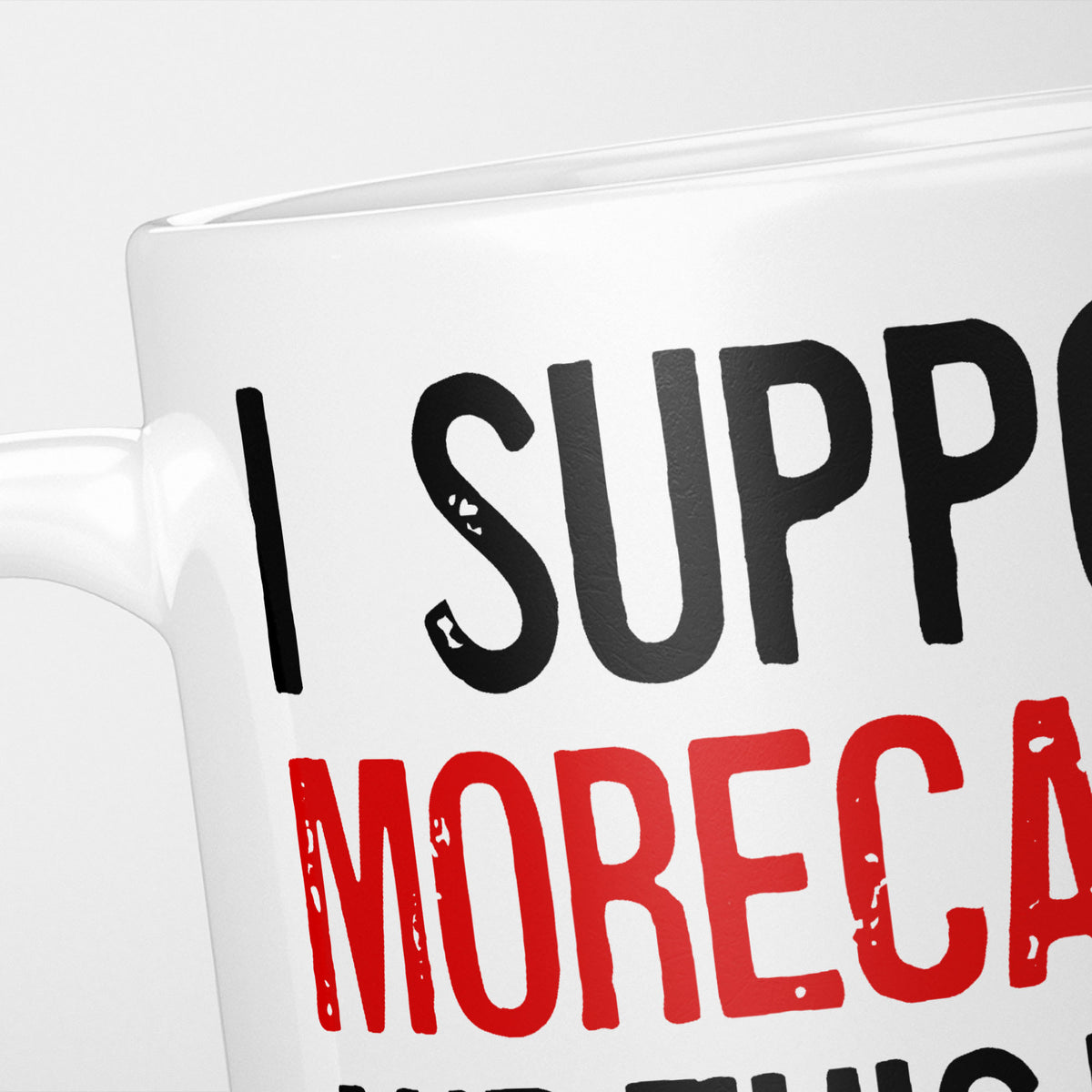 Close crop of the I Support Morecambe mug, 'I Support' in heavy black above the club name in red, running off the edge of the frame