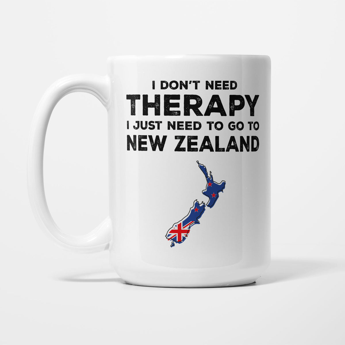 The 15oz I Need New Zealand mug, white ceramic in bold black type reading 'I don't need therapy, I just need to go to NEW ZEALAND', above an outline of New Zealand filled with its national flag
