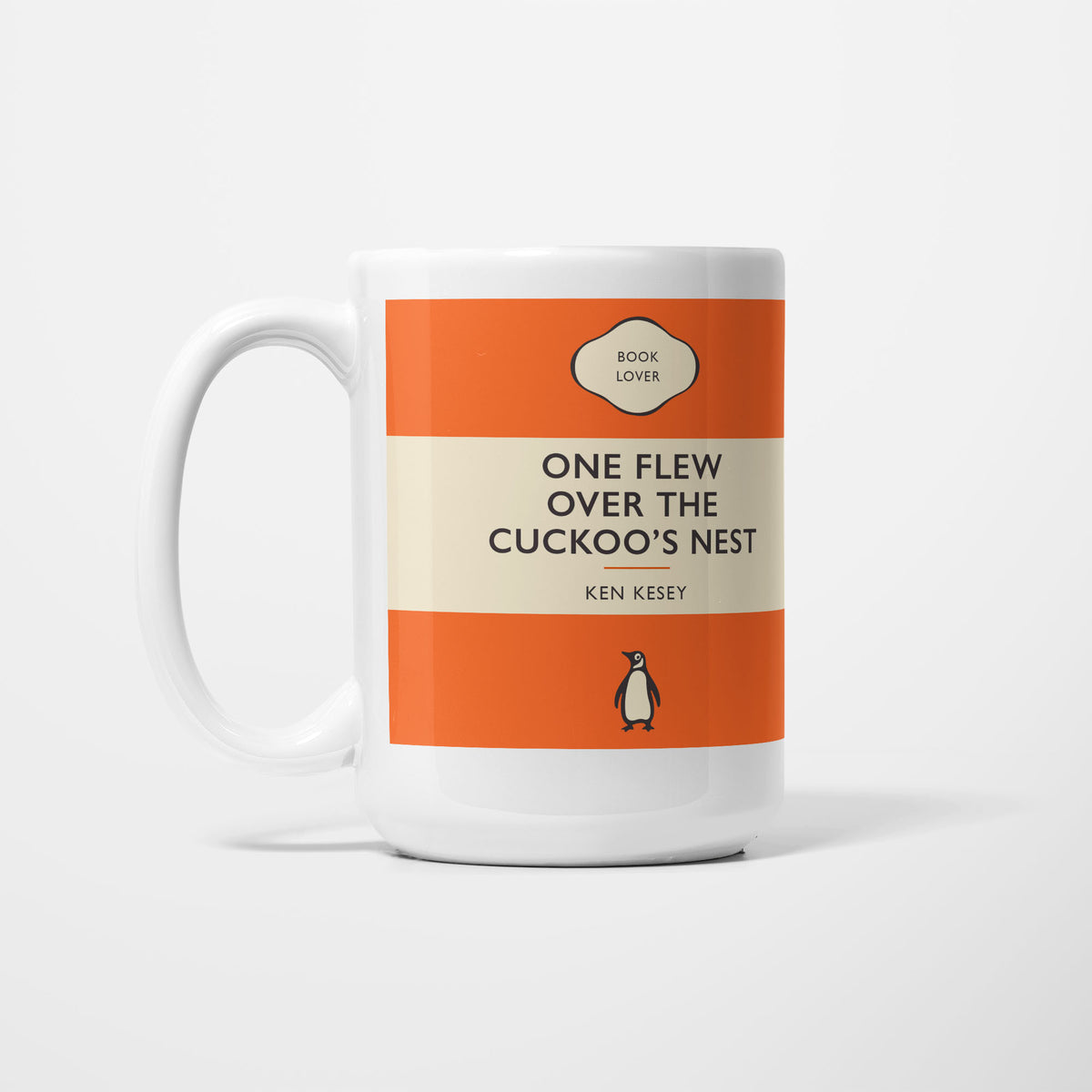 The 15oz One Flew Over the Cuckoo's Nest mug, white ceramic printed as a vintage paperback jacket in orange and cream, reading 'One Flew Over the Cuckoo's Nest' above Ken Kesey