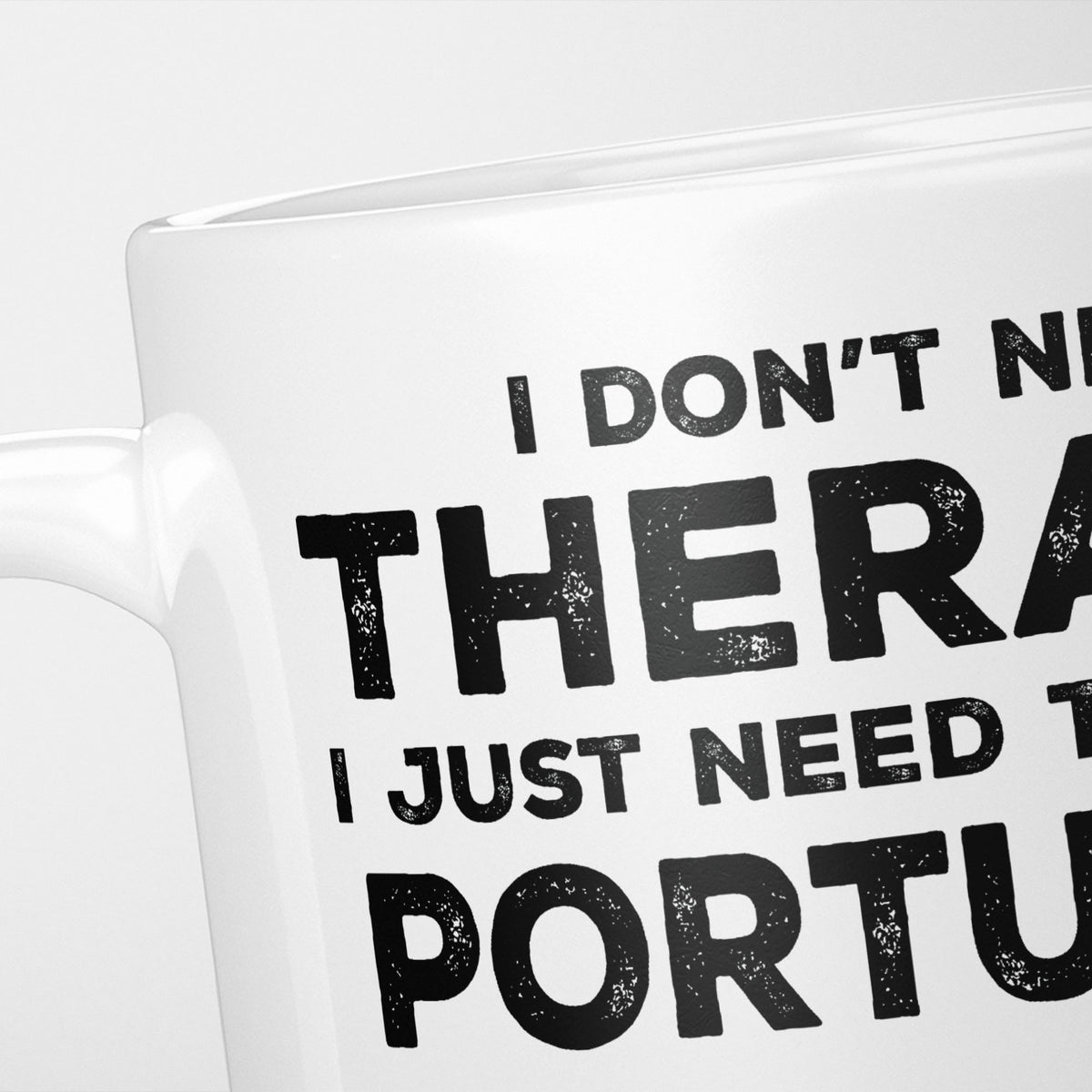 Close crop of the I Need Portugal mug, 'I don't need therapy, I just need to go to PORTUGAL' in heavy distressed black type, running off the edges of the frame