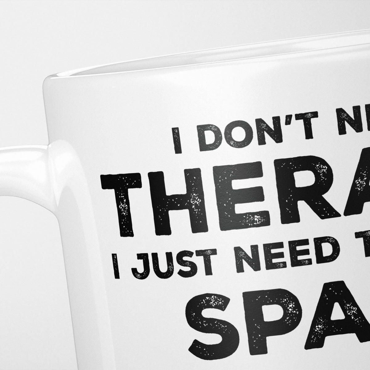 Close crop of the I Need Spain mug, 'I don't need therapy, I just need to go to SPAIN' in heavy distressed black type, running off the edges of the frame