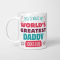 White ceramic mug in retro pink, plum and teal typography reading 'This is what the World's Greatest Daddy looks like', with two curved arrows pointing up at the person holding it and starbursts either side