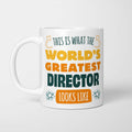 White ceramic mug in retro yellow, orange and dark teal typography reading 'This is what the World's Greatest Director looks like', with two curved arrows pointing up at the person holding it and starbursts either side