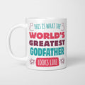White ceramic mug in retro pink, plum and teal typography reading 'This is what the World's Greatest Godfather looks like', with two curved arrows pointing up at the person holding it and starbursts either side