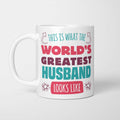White ceramic mug in retro pink, plum and teal typography reading 'This is what the World's Greatest Husband looks like', with two curved arrows pointing up at the person holding it and starbursts either side