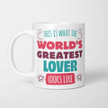 White ceramic mug in retro pink, plum and teal typography reading 'This is what the World's Greatest Lover looks like', with two curved arrows pointing up at the person holding it and starbursts either side