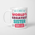 White ceramic mug in retro pink, plum and teal typography reading 'This is what the World's Greatest Sister looks like', with two curved arrows pointing up at the person holding it and starbursts either side