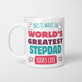 White ceramic mug in retro pink, plum and teal typography reading 'This is what the World's Greatest Stepdad looks like', with two curved arrows pointing up at the person holding it and starbursts either side