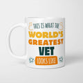 White ceramic mug in retro yellow, orange and dark teal typography reading 'This is what the World's Greatest Vet looks like', with two curved arrows pointing up at the person holding it and starbursts either side